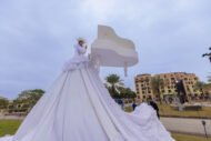 فقرة استعراضية إبداعية بفستان أبيض ضخم بجانب مجسم بيانو في فعالية خارجية من تنظيم Experiume